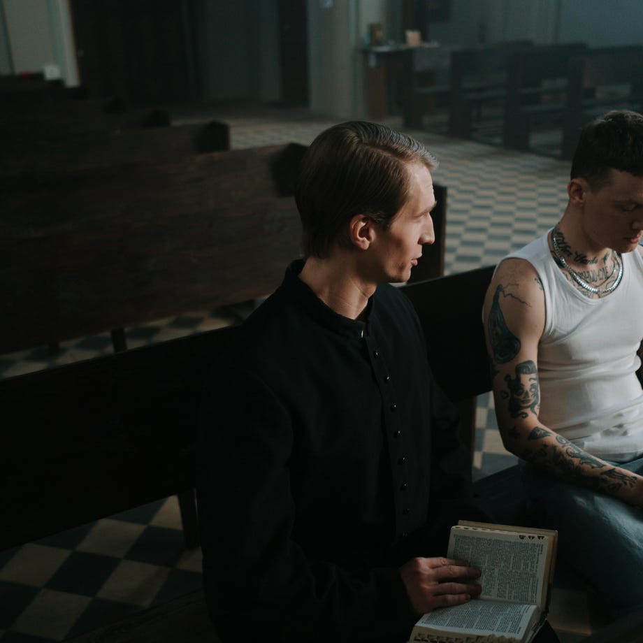 Two men engage in conversation on a church pew, exploring themes of faith and redemption.